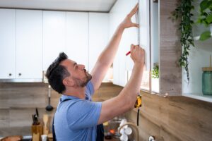 Man carefully measures cabinet heights in a contemporary kitchen during a DIY renovation