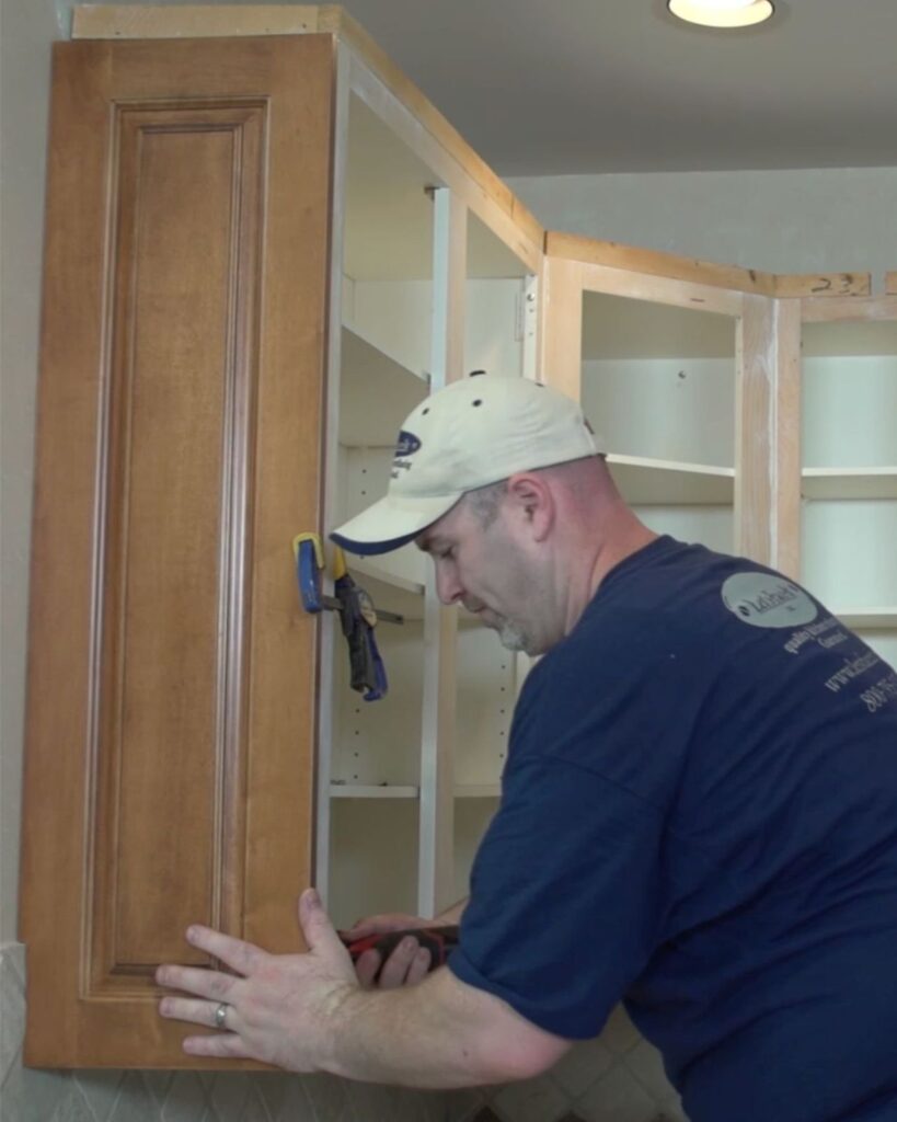 Installer attaching a new cabinet door during cabinet refacing