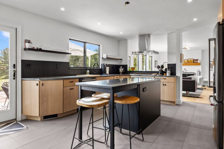 Modern kitchen cabinet refacing with white oak cabinetry, black island, and Platinum Quartzite countertops