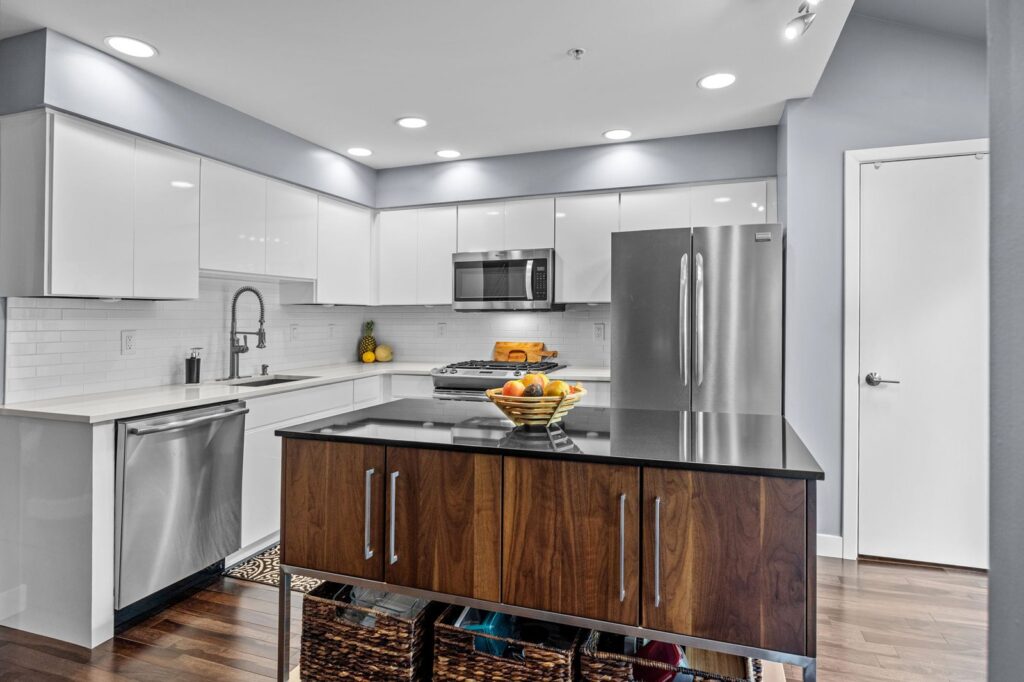 Lower-range cabinet refacing cost example in New Hope PA with glossy white cabinets, walnut island, and black countertops.