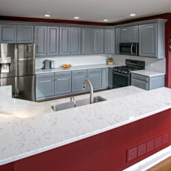 Lyra by Silestone, polished quartz countertops, accented with overcast gray cabinets. white renovated kitchen with red walls